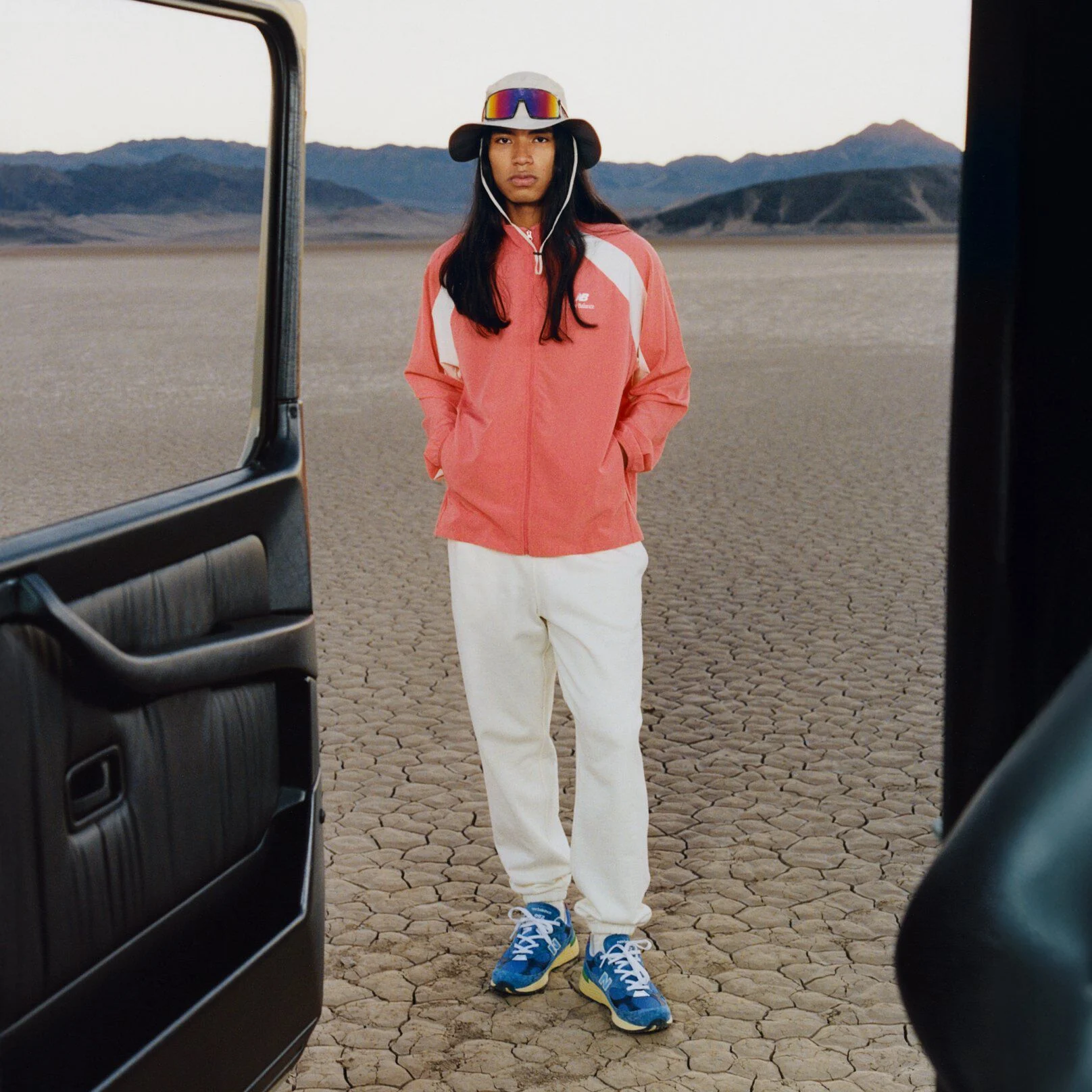Man wearing a bucket hat and an orange jacket with his hands in his jacket pockets.