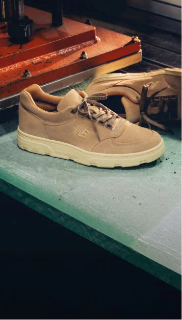 A pair of New Balance Made in UK sneakers on an industrial workshop bench. 