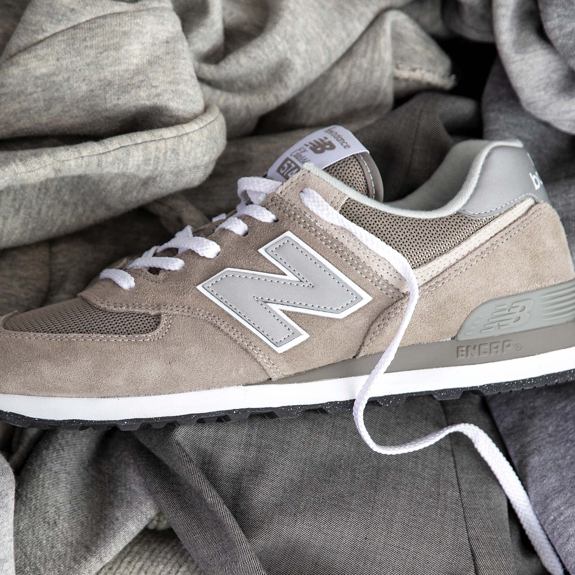 A grey NB 574 sneaker sitting on top of a pile of grey garments
