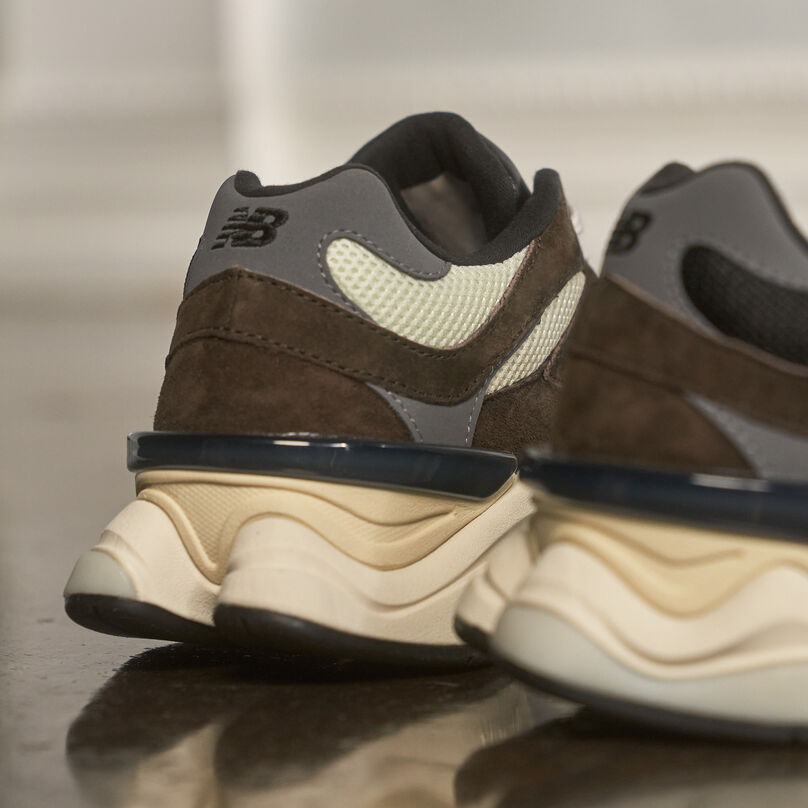 Back of the brown shoes, showing the split midsole sitting on a reflective floor.