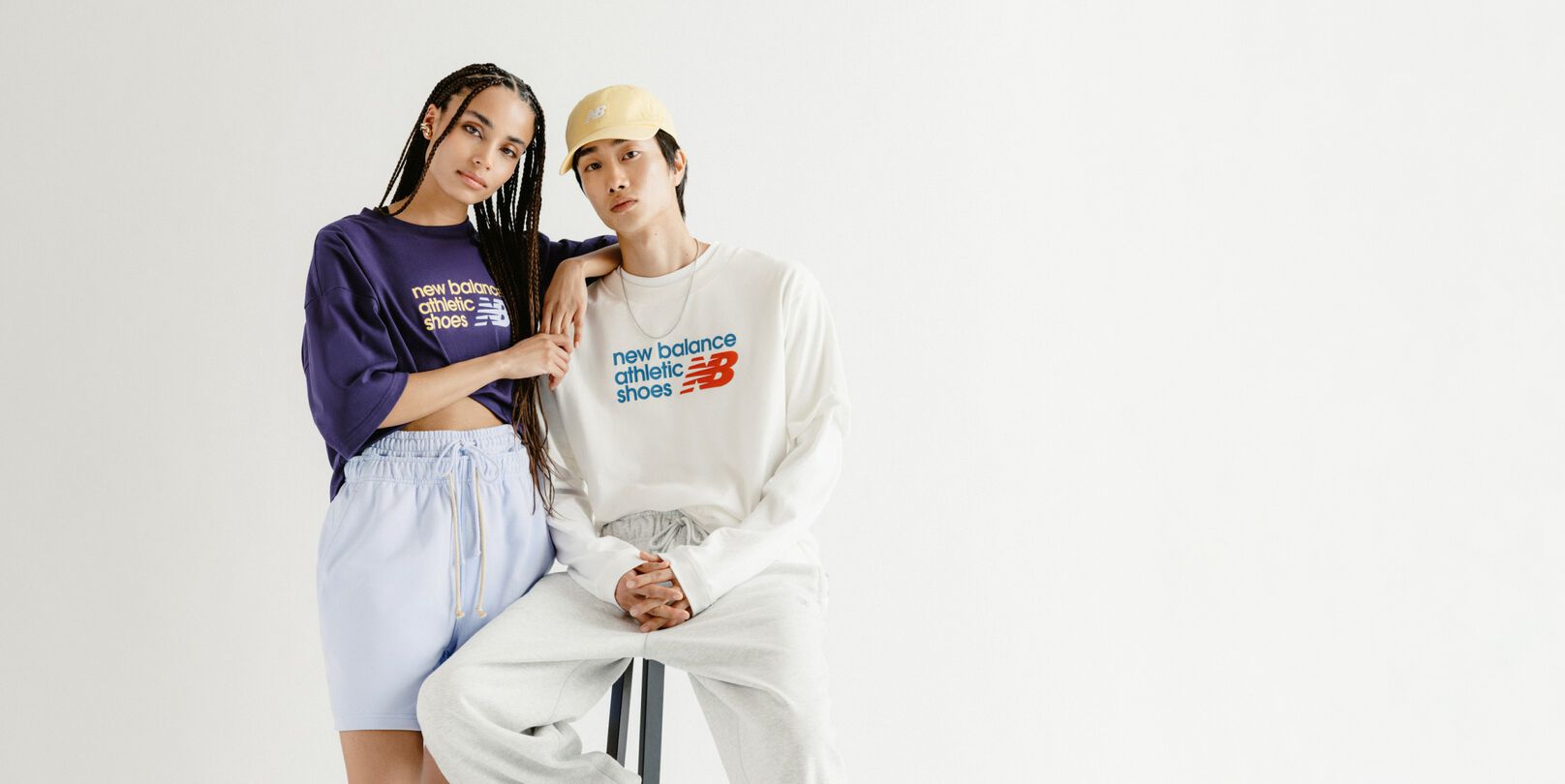 A man and woman in front of a grey studio backdrop.