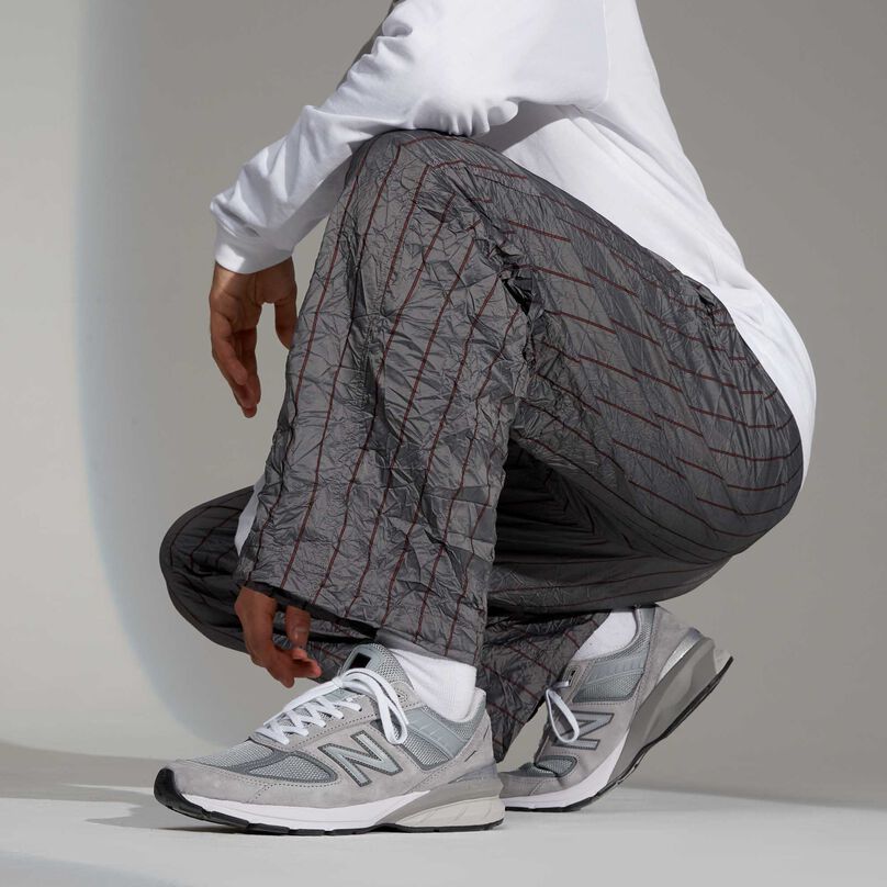 Grey 990 men’s sneakers styled with striped grey pants