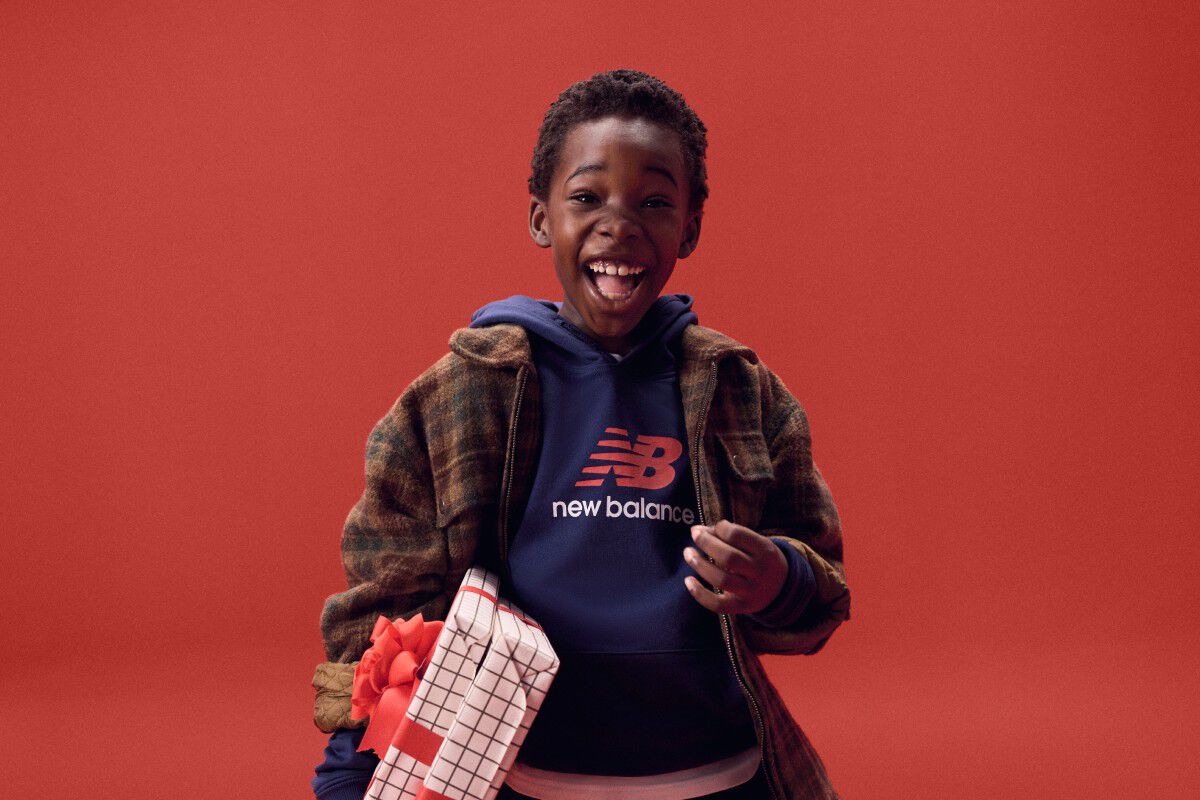 Niño riendo mientras sostiene regalos sobre un fondo rojo.