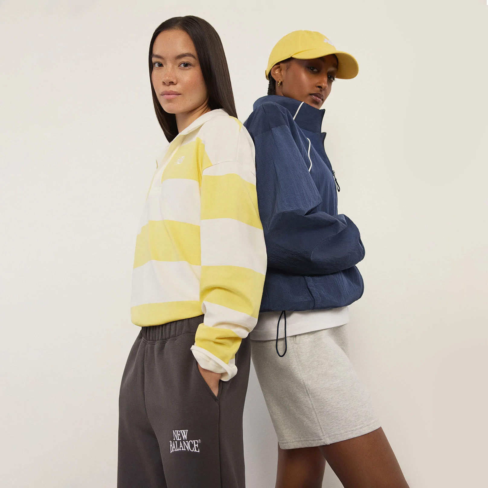 Two women standing in front of a white wall.