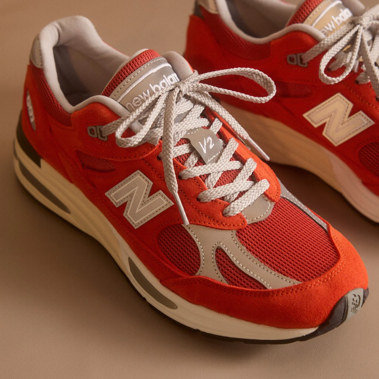 Primer plano de un par de zapatillas New Balance Made in UK en un estudio de color beige.&nbsp;