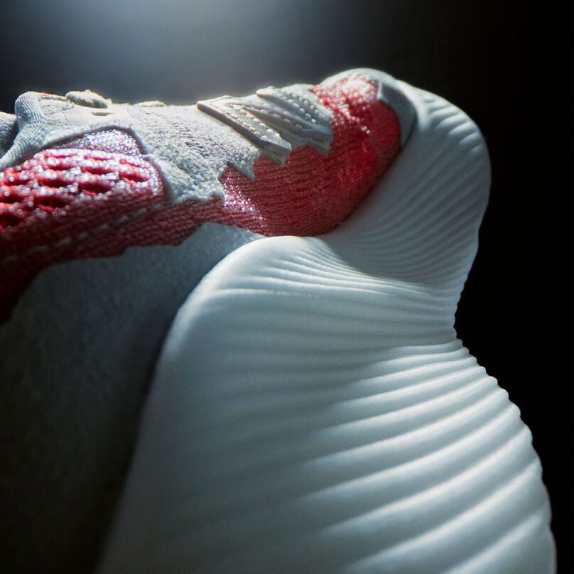 A dramatically lit detail shot of the heel and inside upper of a NB Stone Island Tokyo Design Studio light grey FuelCell RC Elite running shoe with red accents