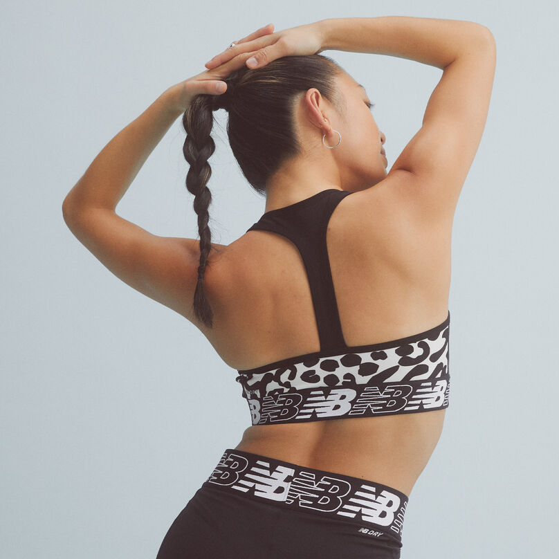 Back view of a woman wearing a black and white NB Pace Bra with black bike shorts