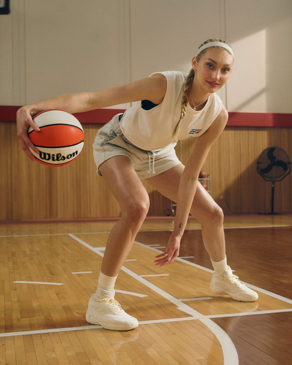 Cameron Brink on an indoor basketball court is captured mid‑dribble, leaning low in an athletic stance while holding a basketball.