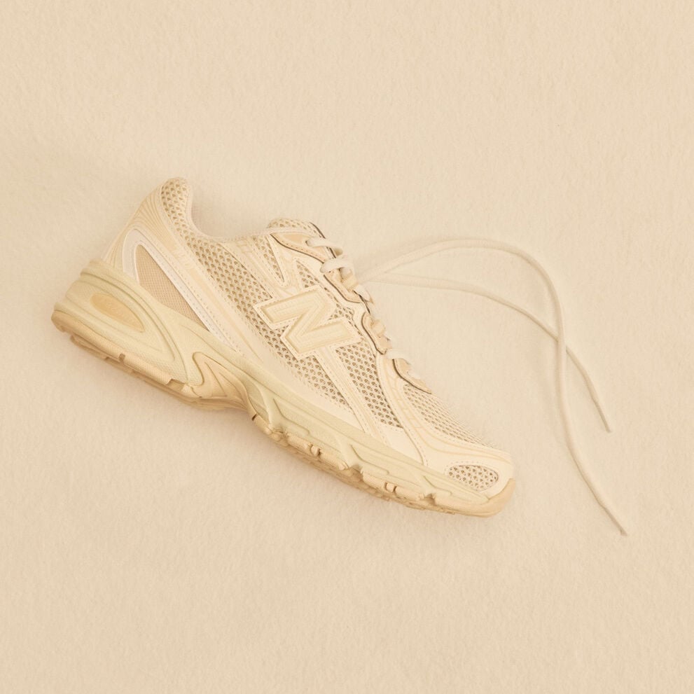 A tan shoe laying on a tan studio backdrop.