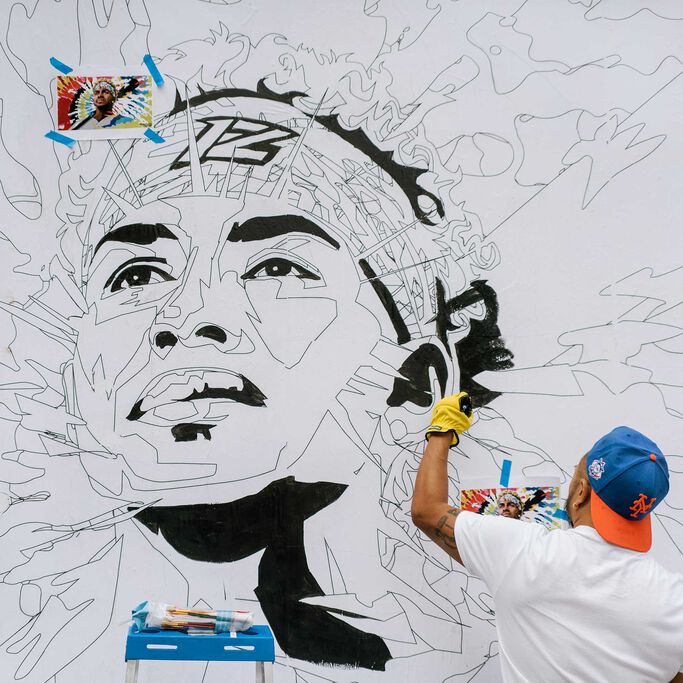 Glen Infante standing painting the Lindor Mural.