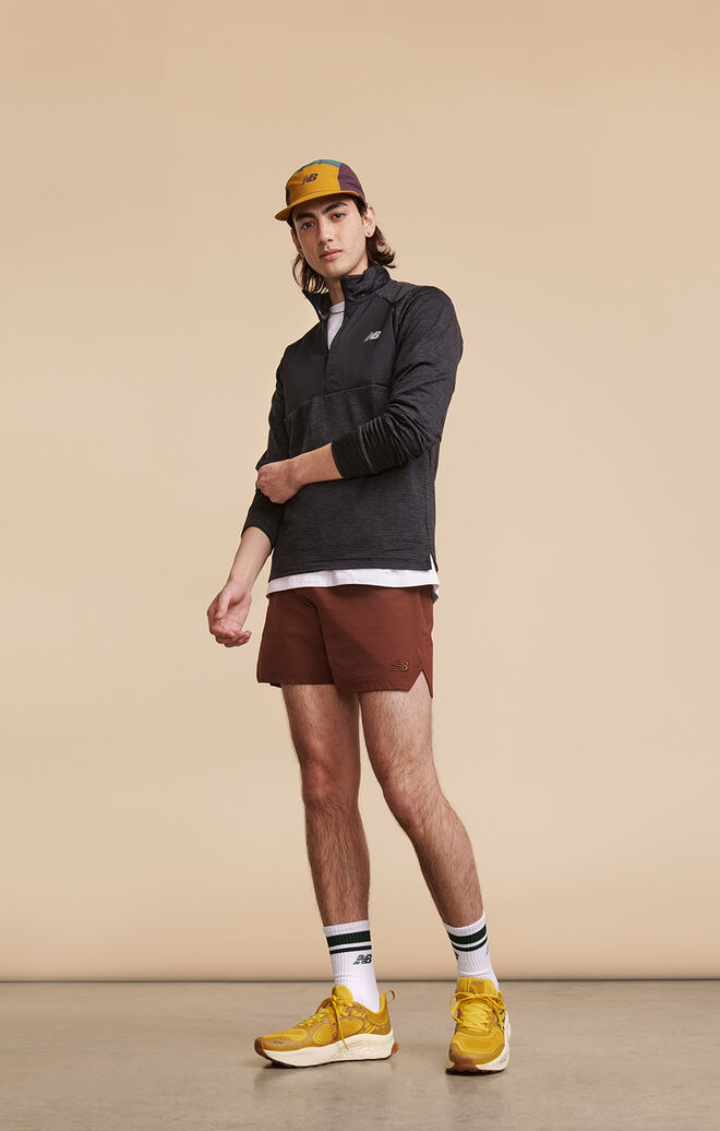 Man wearing New Balance running clothing and shoes posed against beige background in studio environment 