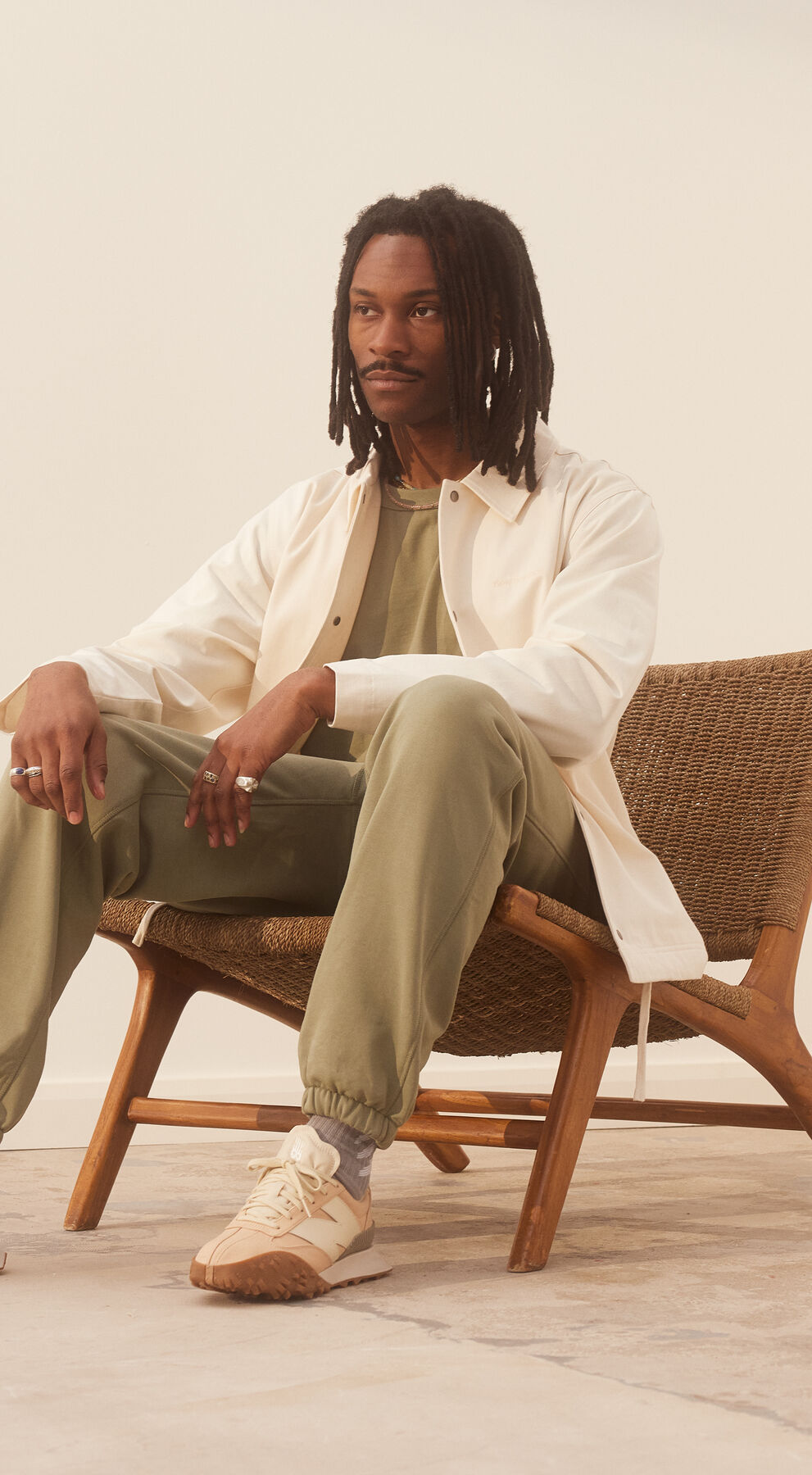 Young man sitting in a room with earth tone colors on his outfit.