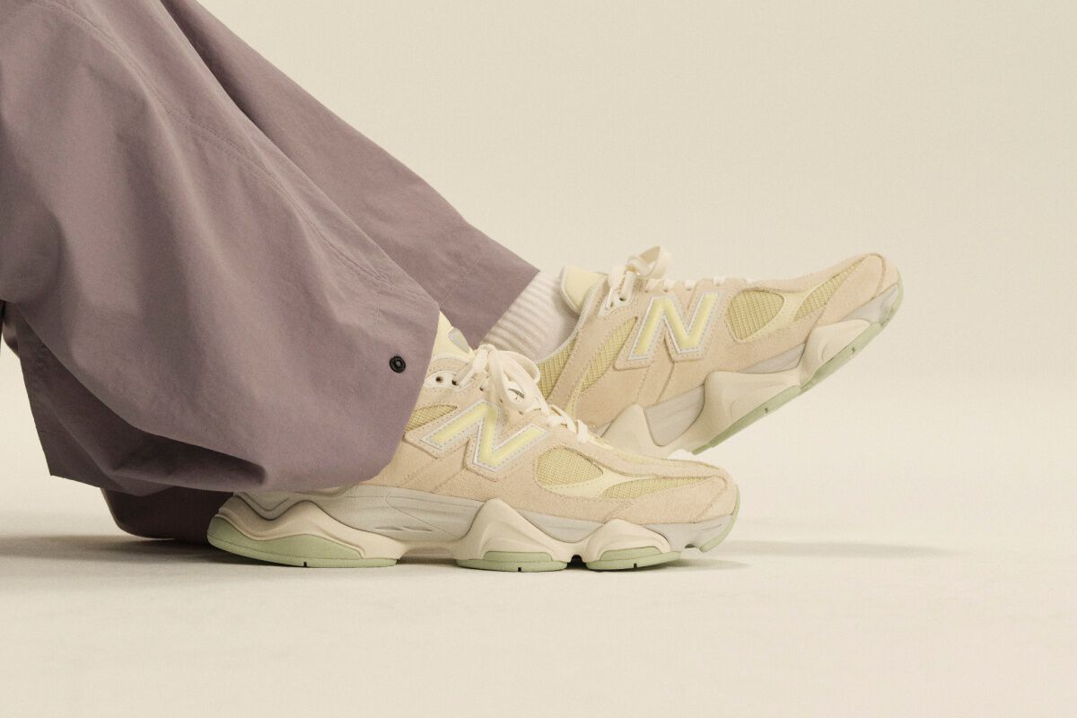 Close-up of cream New Balance athletic sneakers paired with white crew socks and lavender wide-leg pants in a clean studio setting.