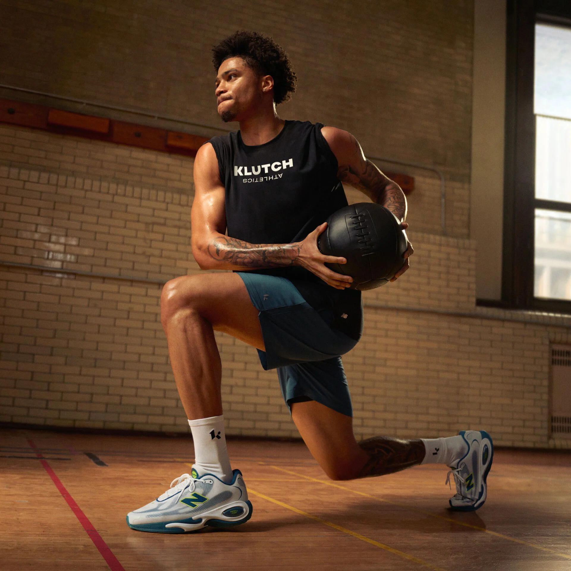 Athlete performing a weighted lunge with a medicine ball on an indoor gym court while wearing New Balance training shoes.