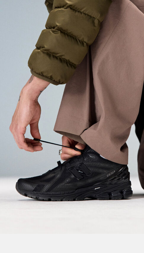 Closeup of an individual kneeling down to tie the laces on the 1906R 