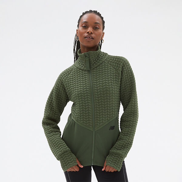 Woman wearing an olive-green NB Heat Grid long sleeve top and black NB tights