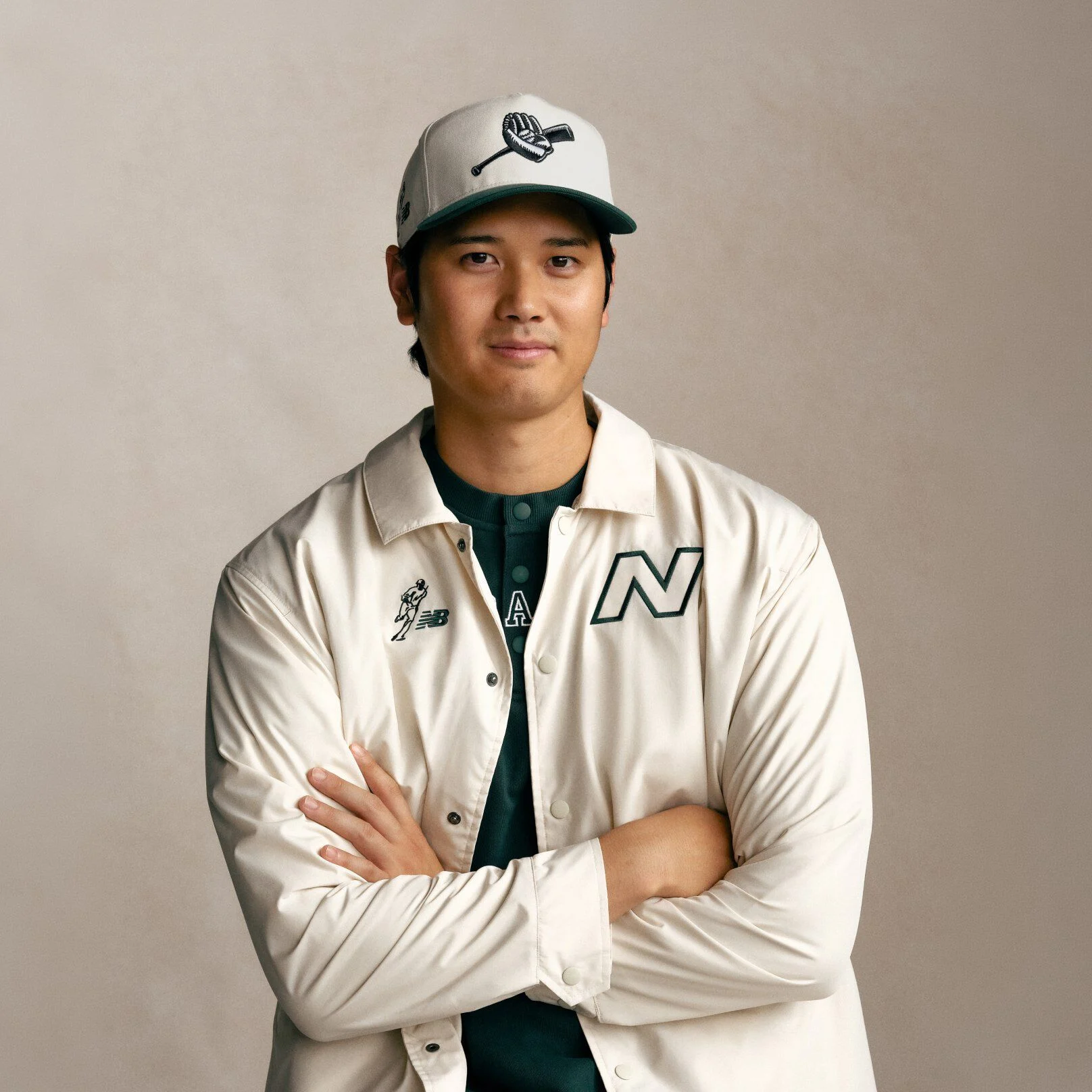Ohtani wearing a white hat and jacket with his arms folded and smiling.