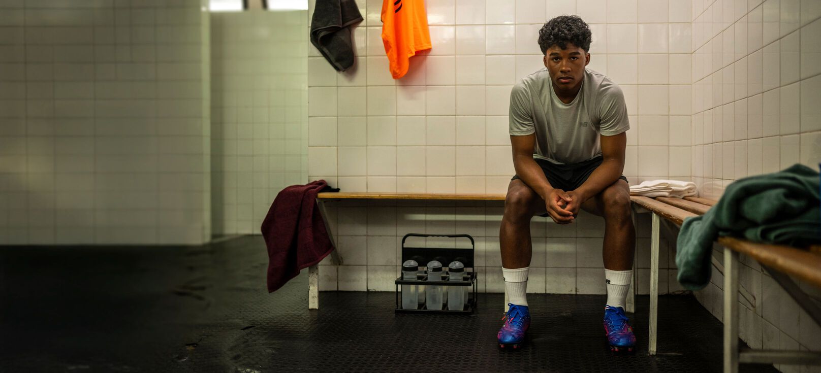 Endrick sitting in a locker room, wearing New Balance Tekela soccer cleats.   