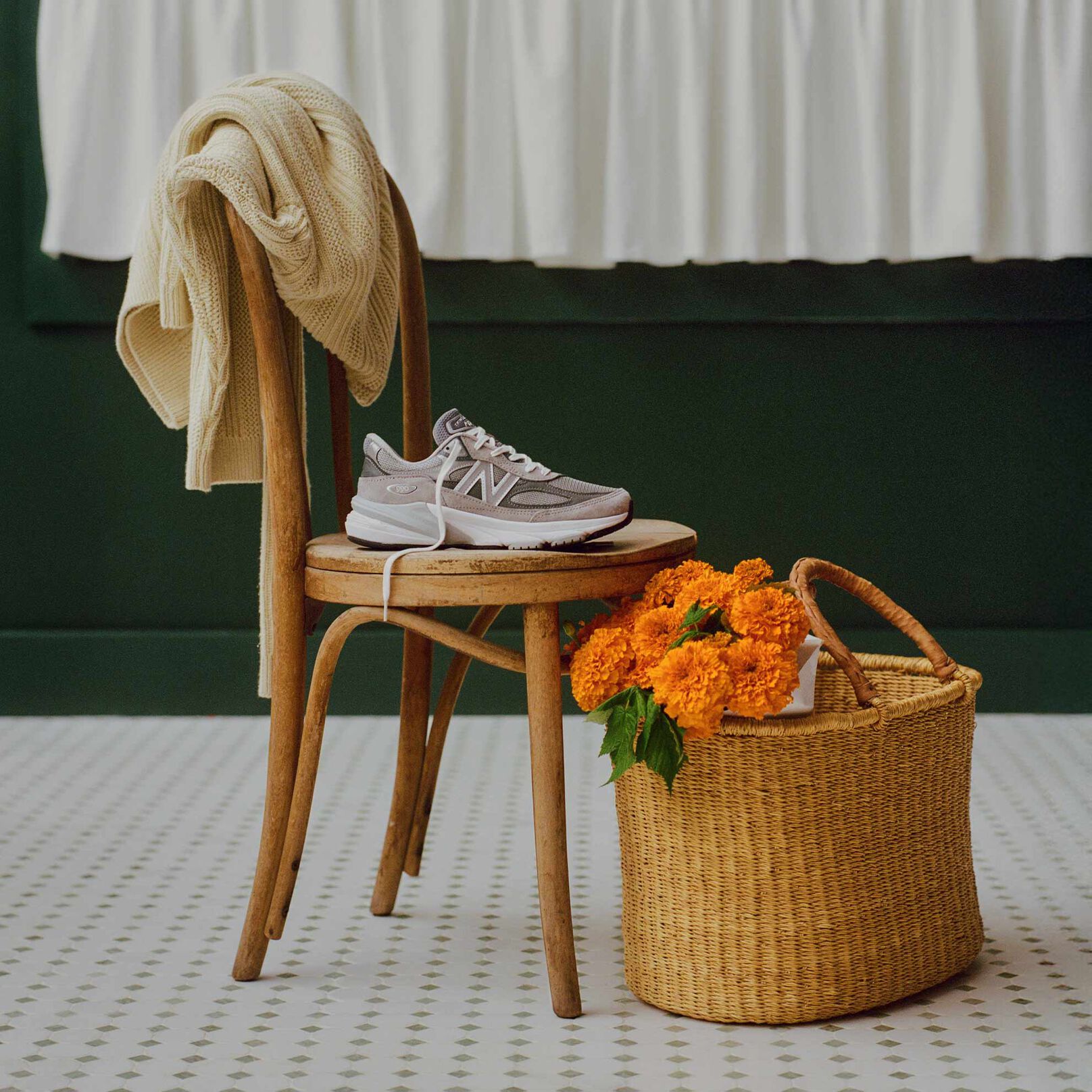 A grey 990v6 sneaker sitting on a chair in a cafe environment.