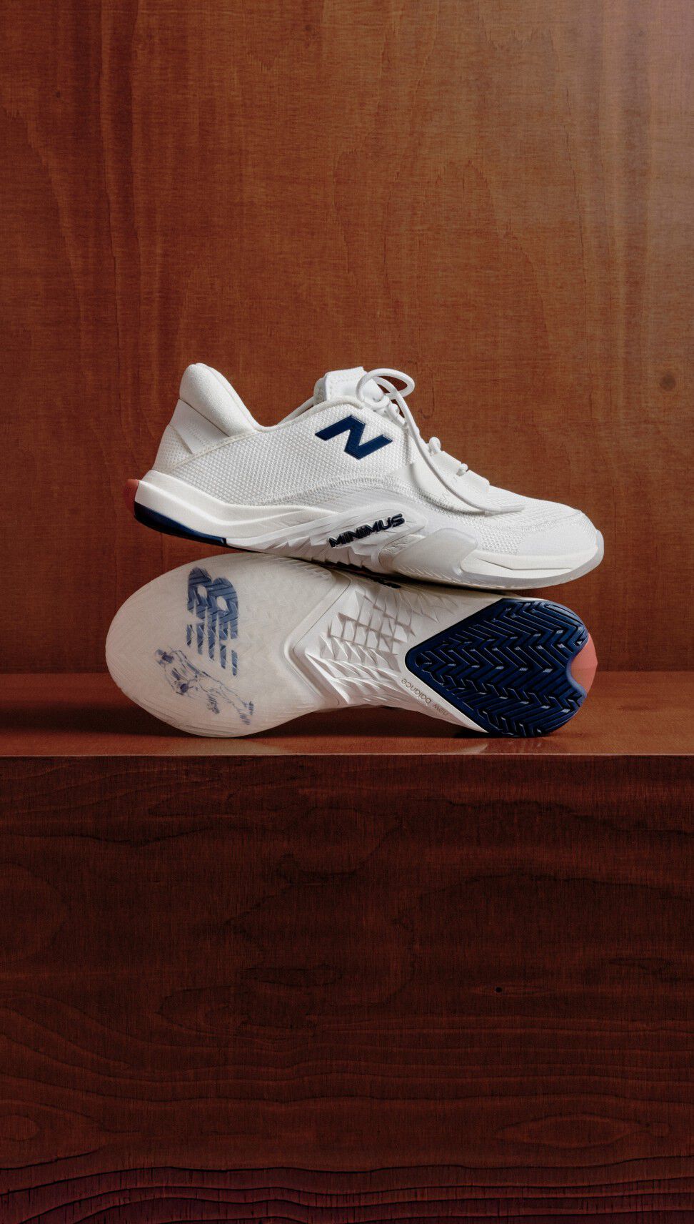Pair of white workout shoes sitting on top of each other on a wooden bench. 