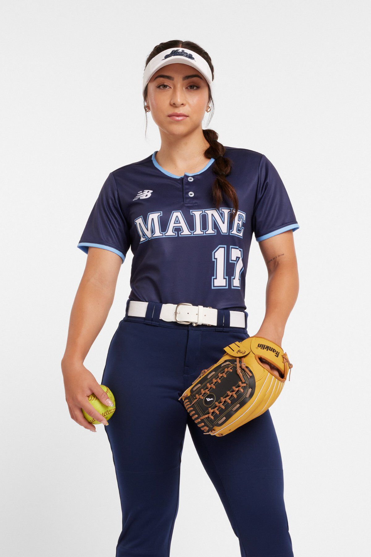 Woman wearing a navy softball jersey reading &ldquo;MAINE&rdquo; with number 17, navy pants, white visor, and holding a softball glove and ball.
