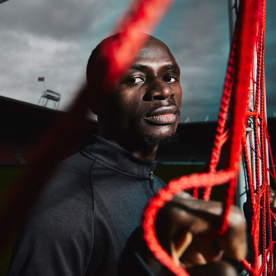 Footballer Sadio Mane on dark, moody soccer pitch.