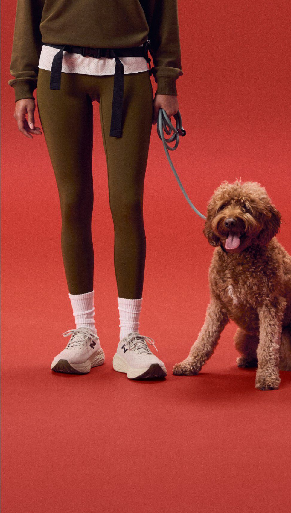 Young woman standing on a red background holding a dog.