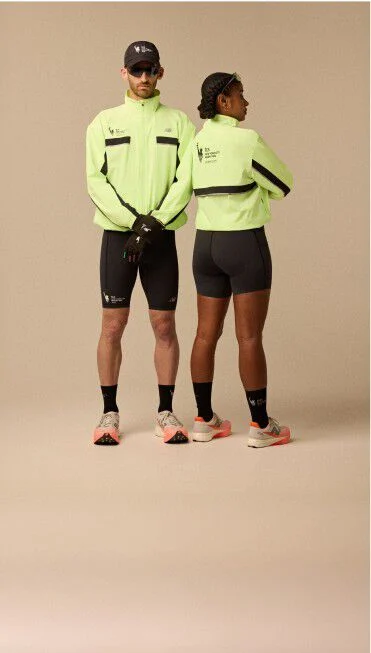 A man and woman wearing neon yellow jacket and running apparel in front of a beige background.