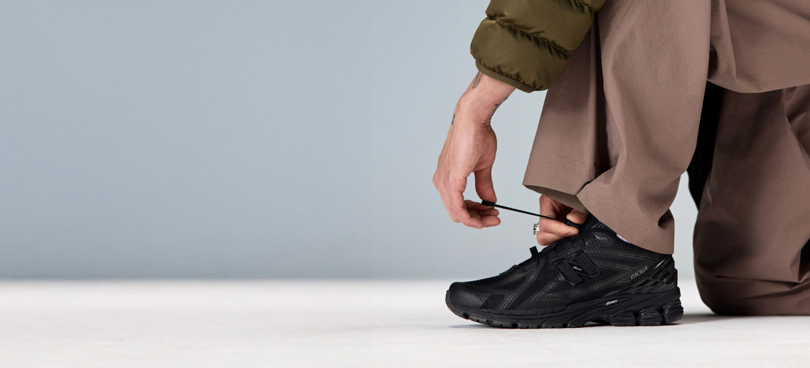 Closeup of an individual kneeling down to tie the laces on the 1906R