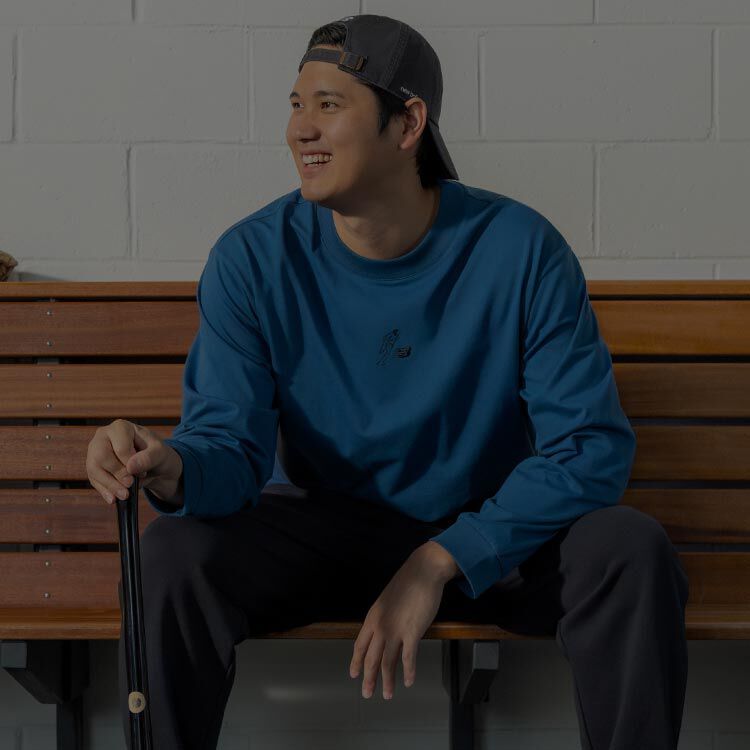 Shoehei Ohtani sitting in a locker room in a blue jacket. 