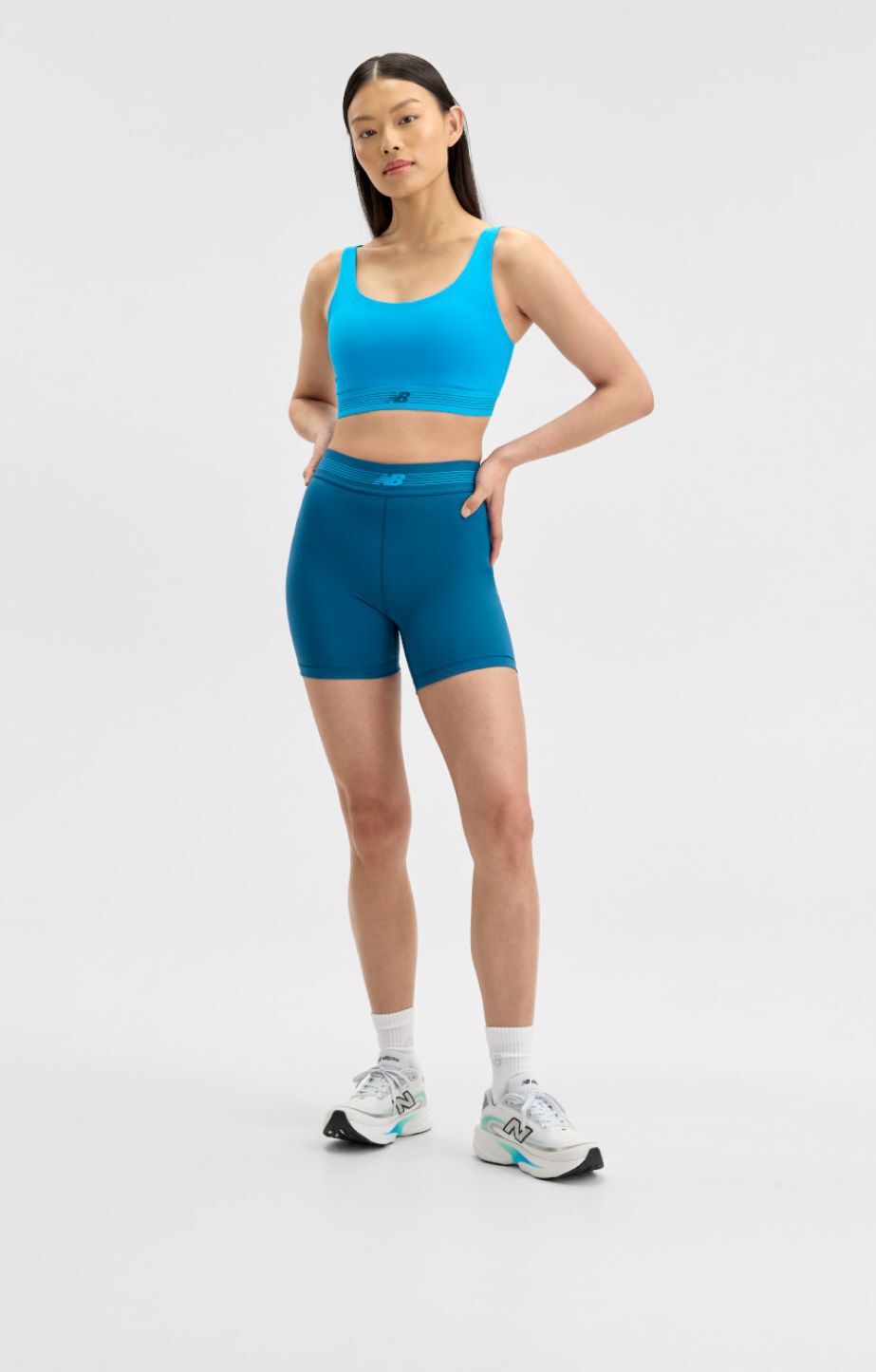 mujer usando ropa azul de New Balance sobre un fondo blanco.