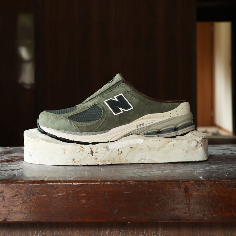 Profile of the green slip on shoe sitting on a stone in a workshop.