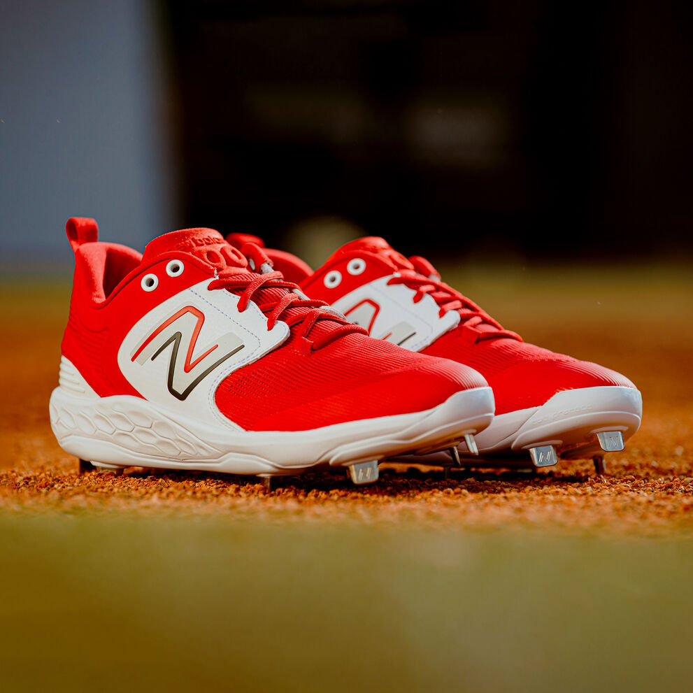 Red and white metal cleat sitting on a baseball field. 