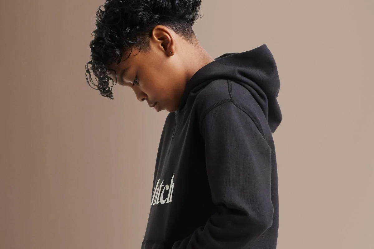 Kid in a black hoodie looking at the ground.