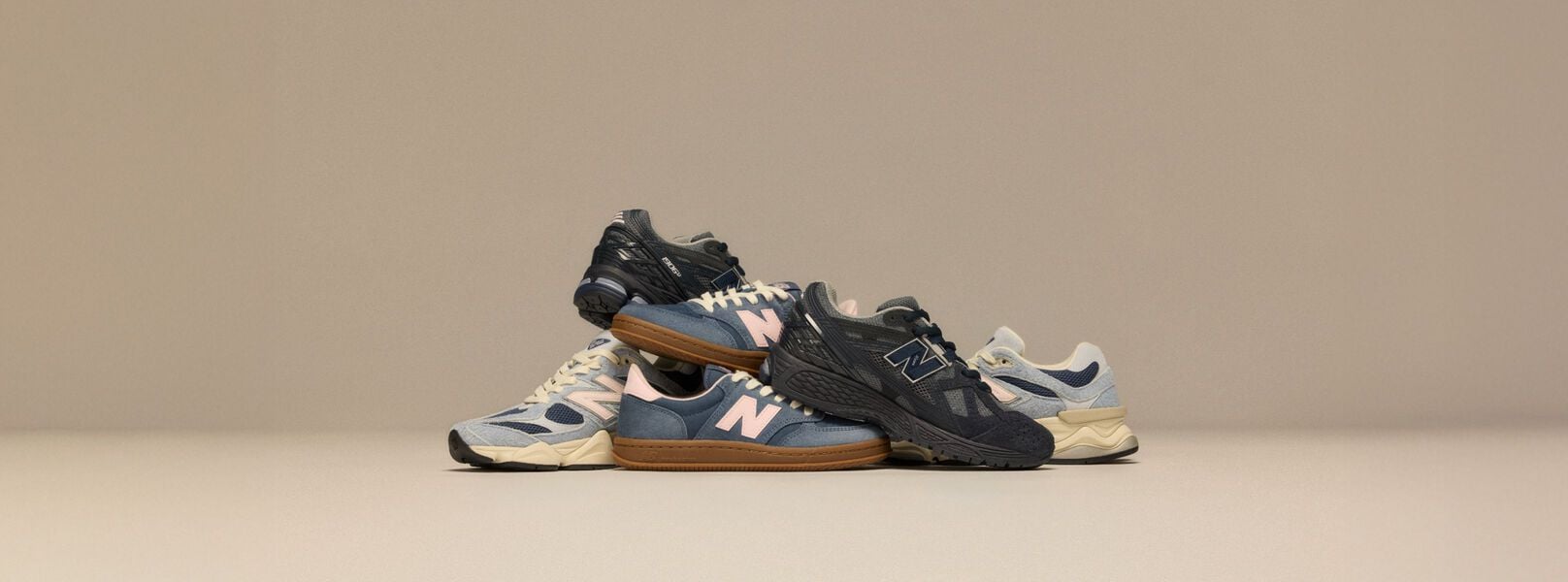 Pile of New Balance sneakers on beige background 