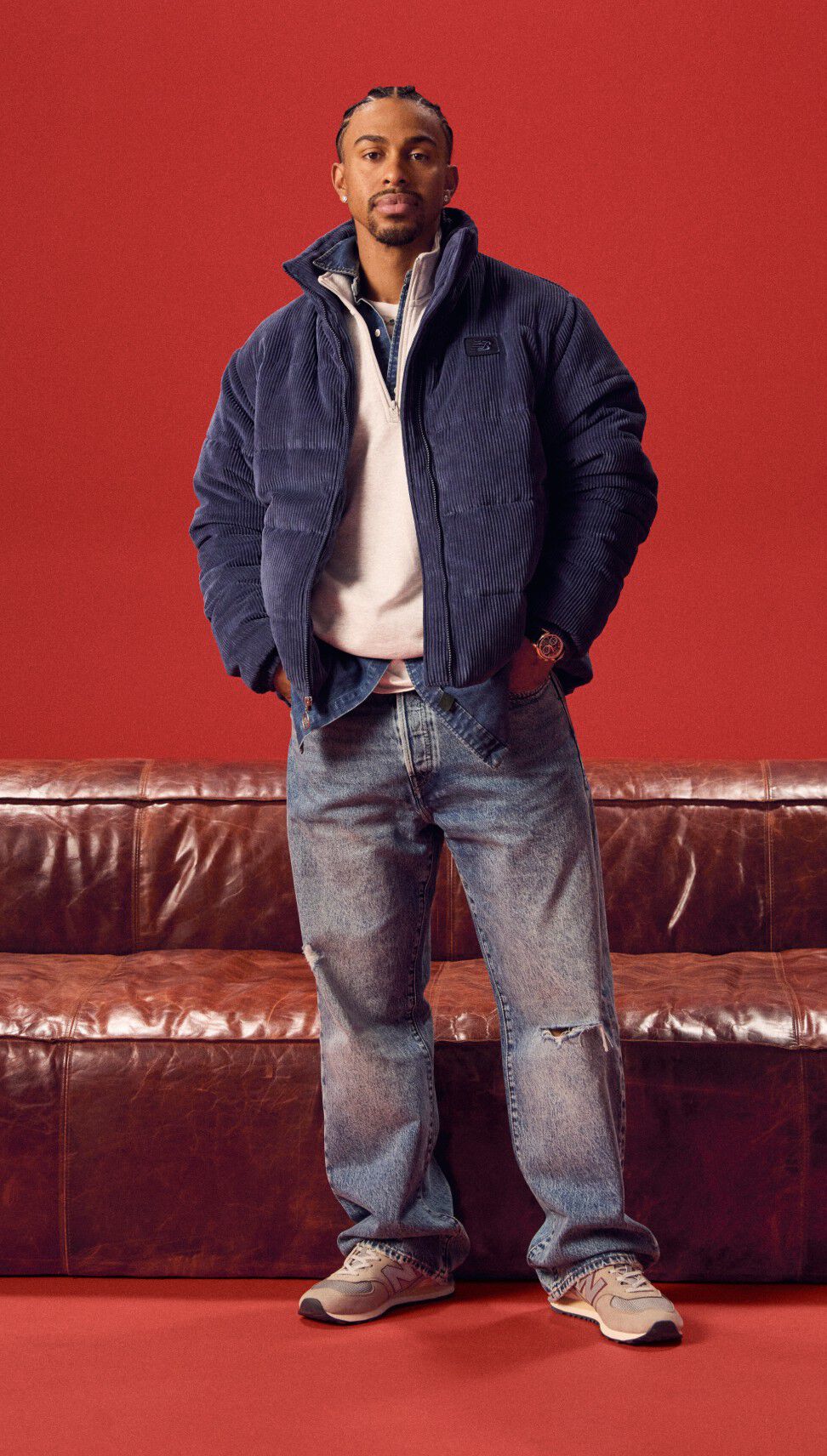 Lindor in a navy jacket standing in front of a red couch.