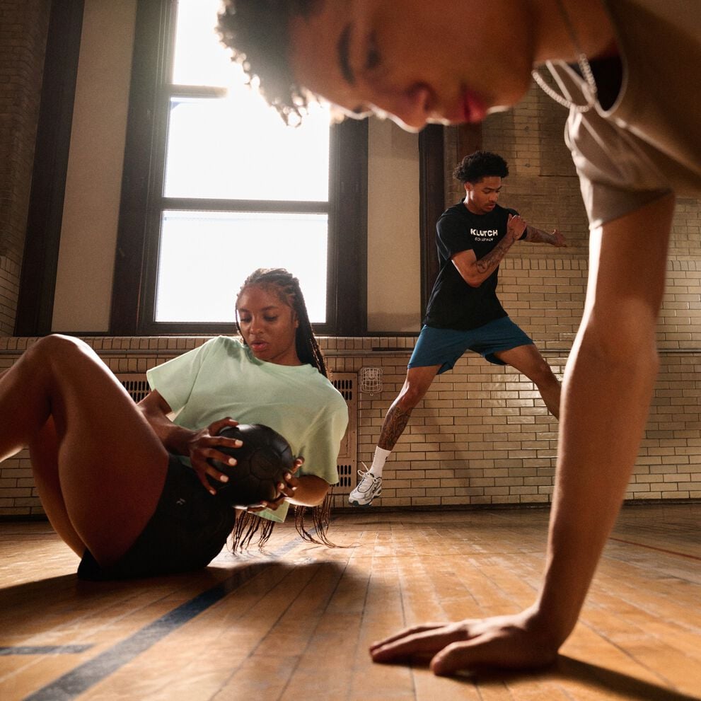 Person using battle ropes during an outdoor workout session with another participant on a rooftop training area.