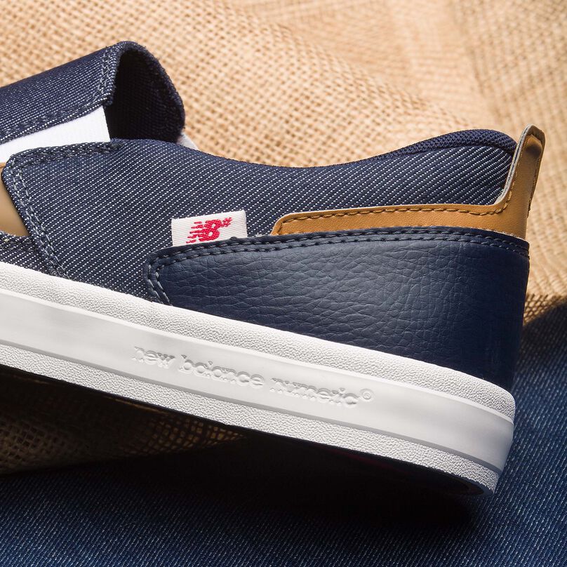 A crop of the heel and mid-section of a laceless denim NB Numeric 306 skate shoe sitting atop denim and burlap fabrics