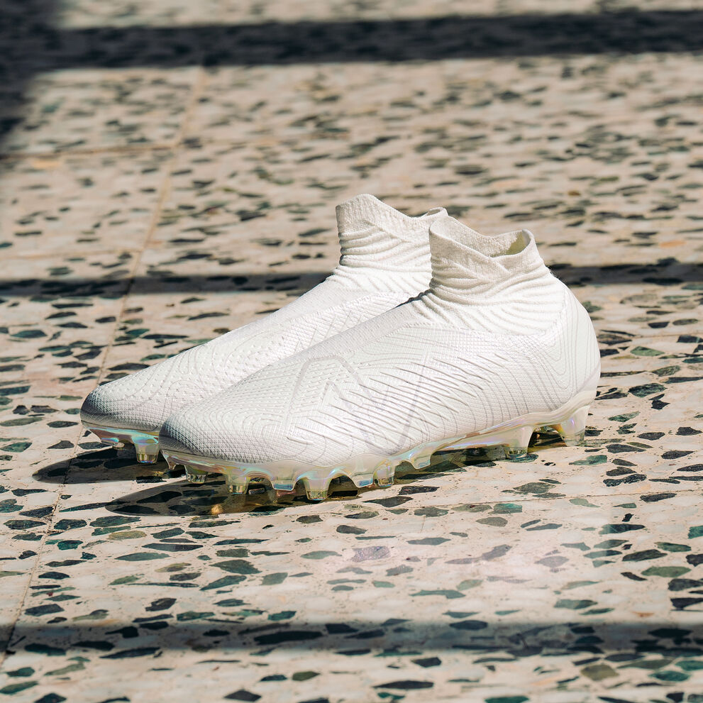 All white soccer cleat sitting on a marbled floor. 
