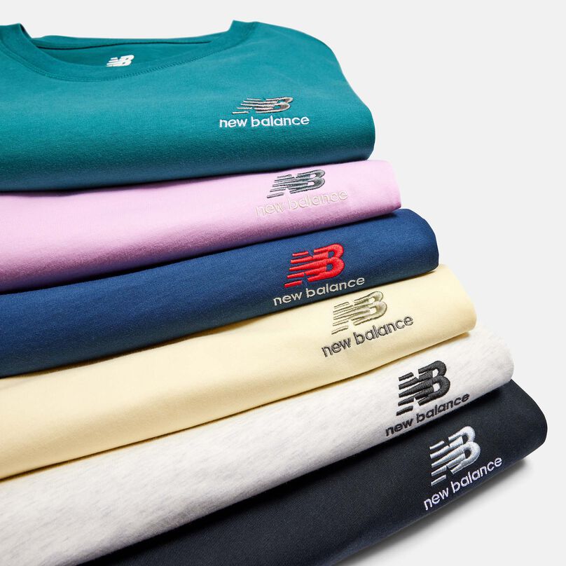 Crop of a stack of various colors of NB Uni-ssentials t-shirts 