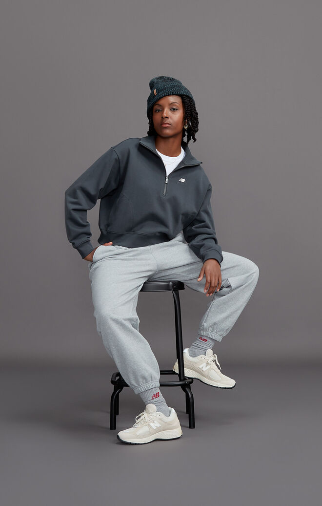 A young woman sitting on a stool wearing head-to-toe grey NB gear