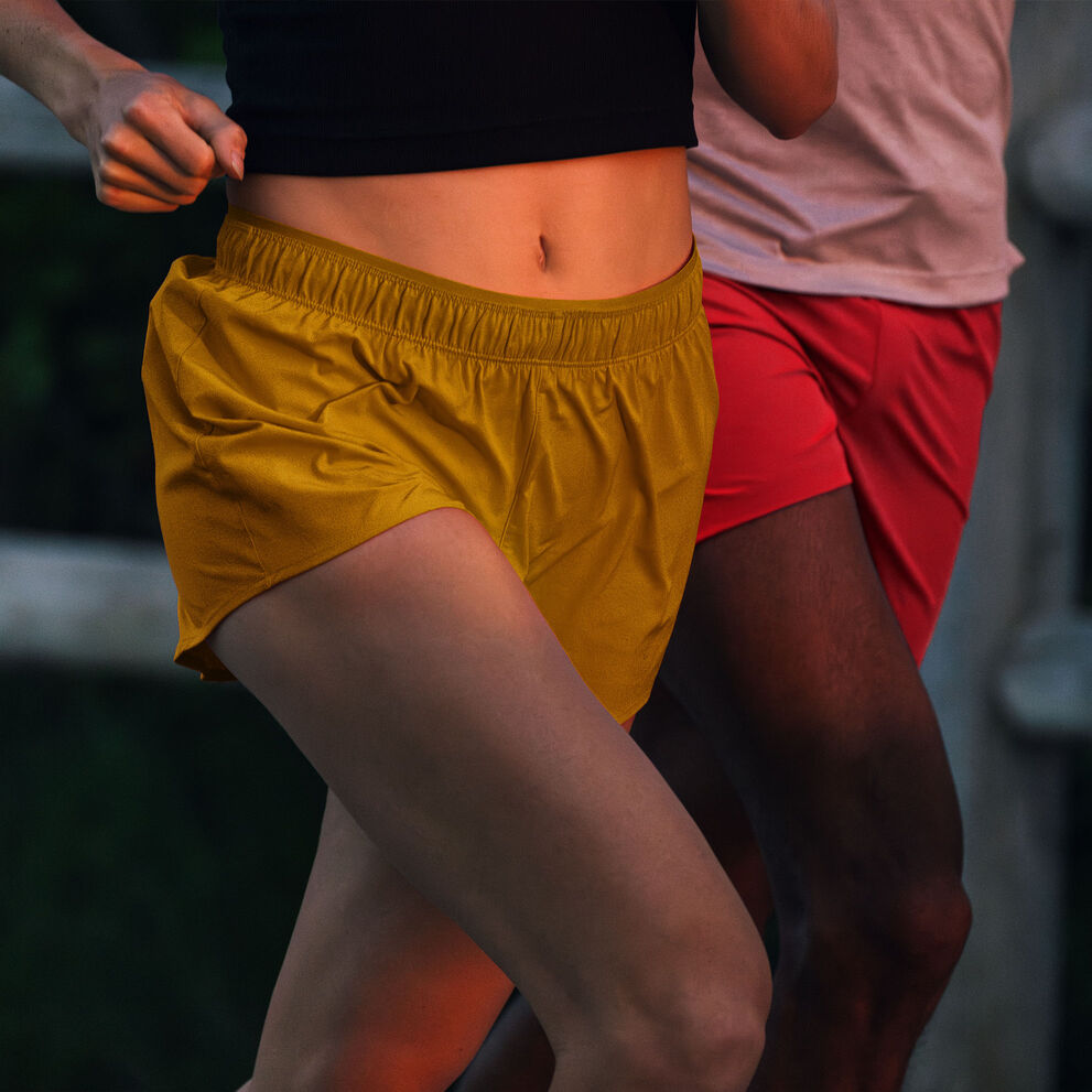 Two individuals running outside, wearing New Balance RC Shorts.