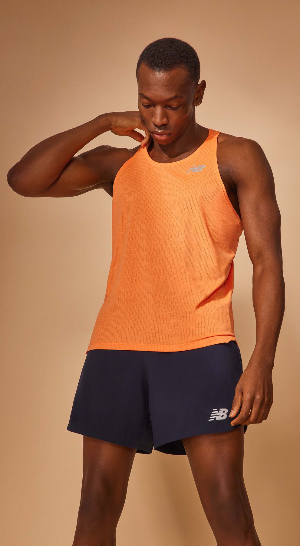 Waist-up crop of a man posing in a vibrant orange NB Impact Run Singlet with indigo NB Impact Run 5 Inch Shorts