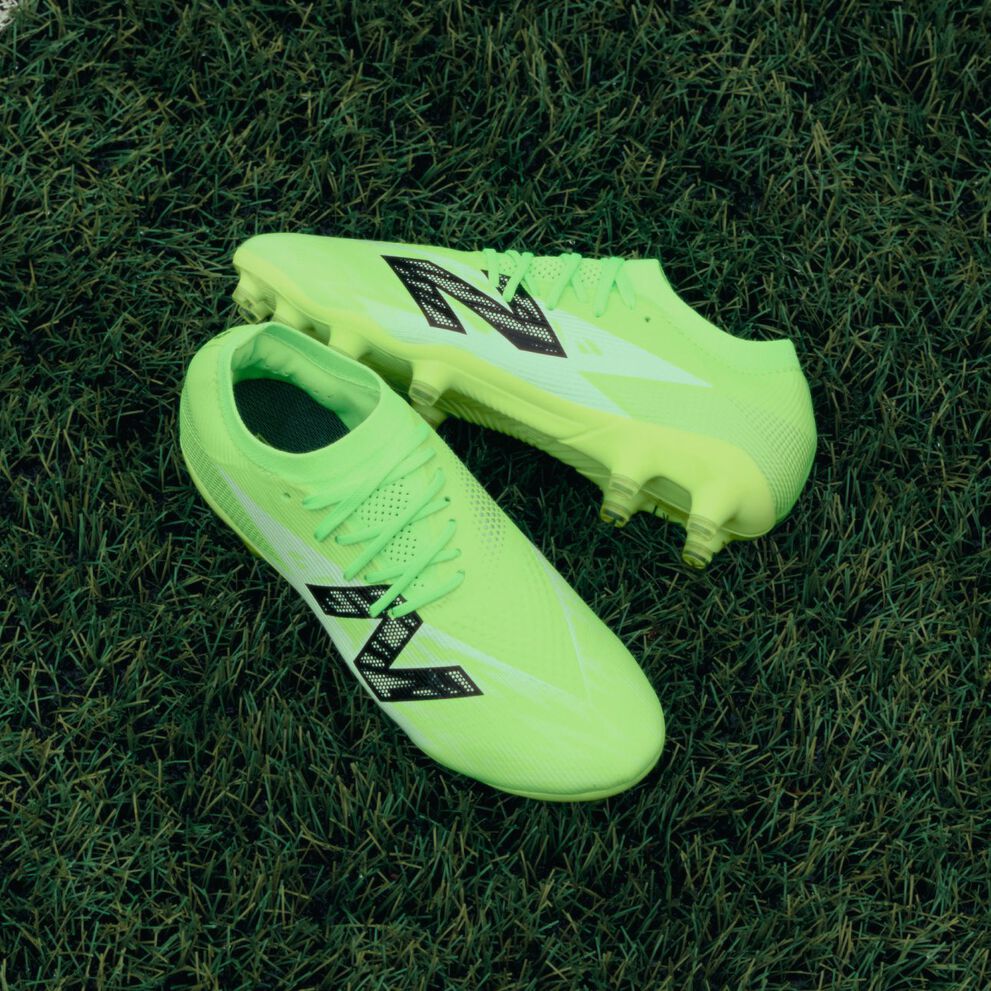 Pair of neon green cleats laying on the pitch.