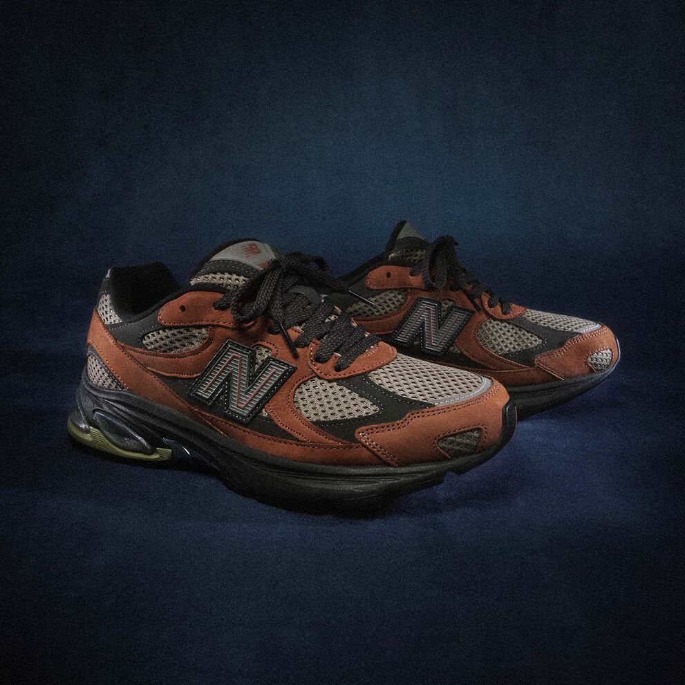 A brown pair of ABZORB 2010 sneakers sitting on a blue studio backdrop.