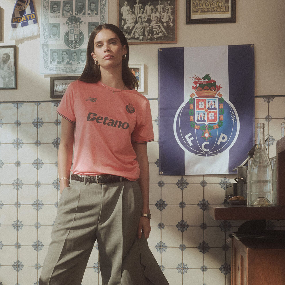 Sara Sampaio standing in a cafe environment wearing the FC Porto Away kit. 