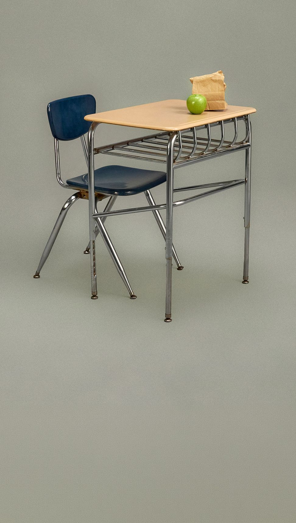 Escritorio y silla del colegio sobre fondo gris.