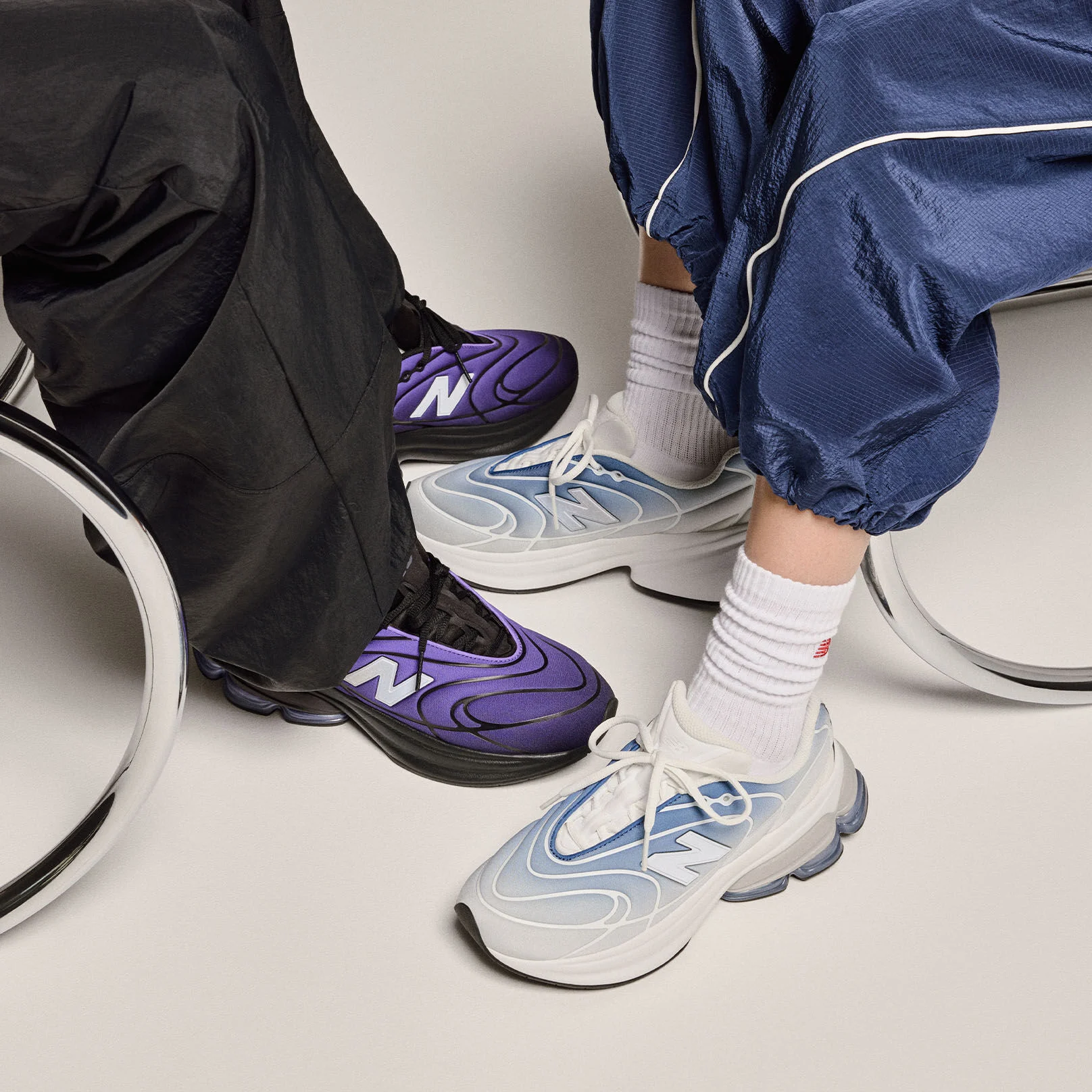 Knee-down view of two people wearing sneakers on a beige background. 