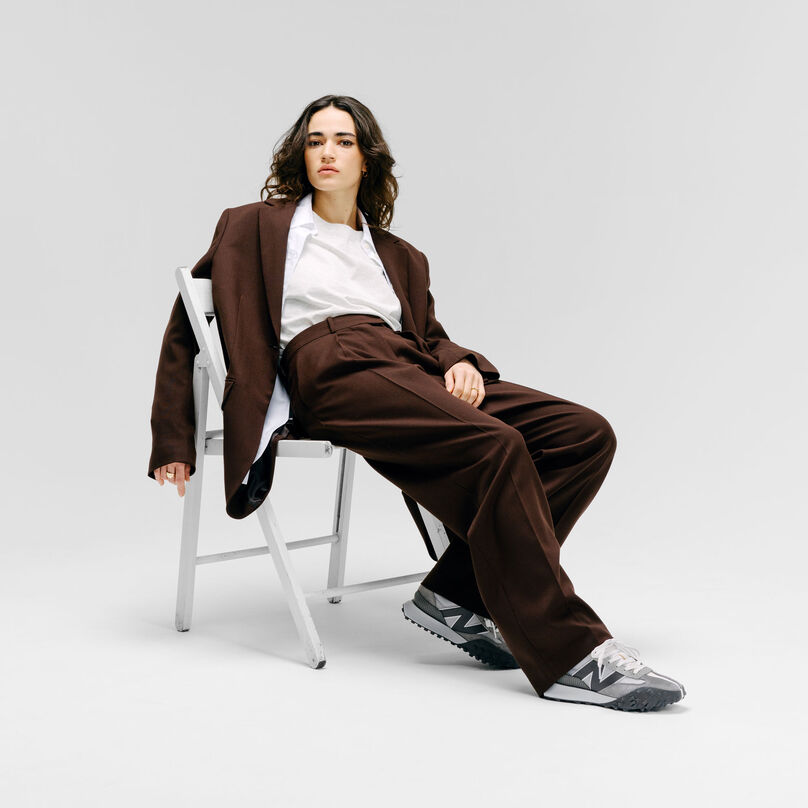 Woman sitting on a chair in a grey studio backdrop wearing the Grey Day XC-72