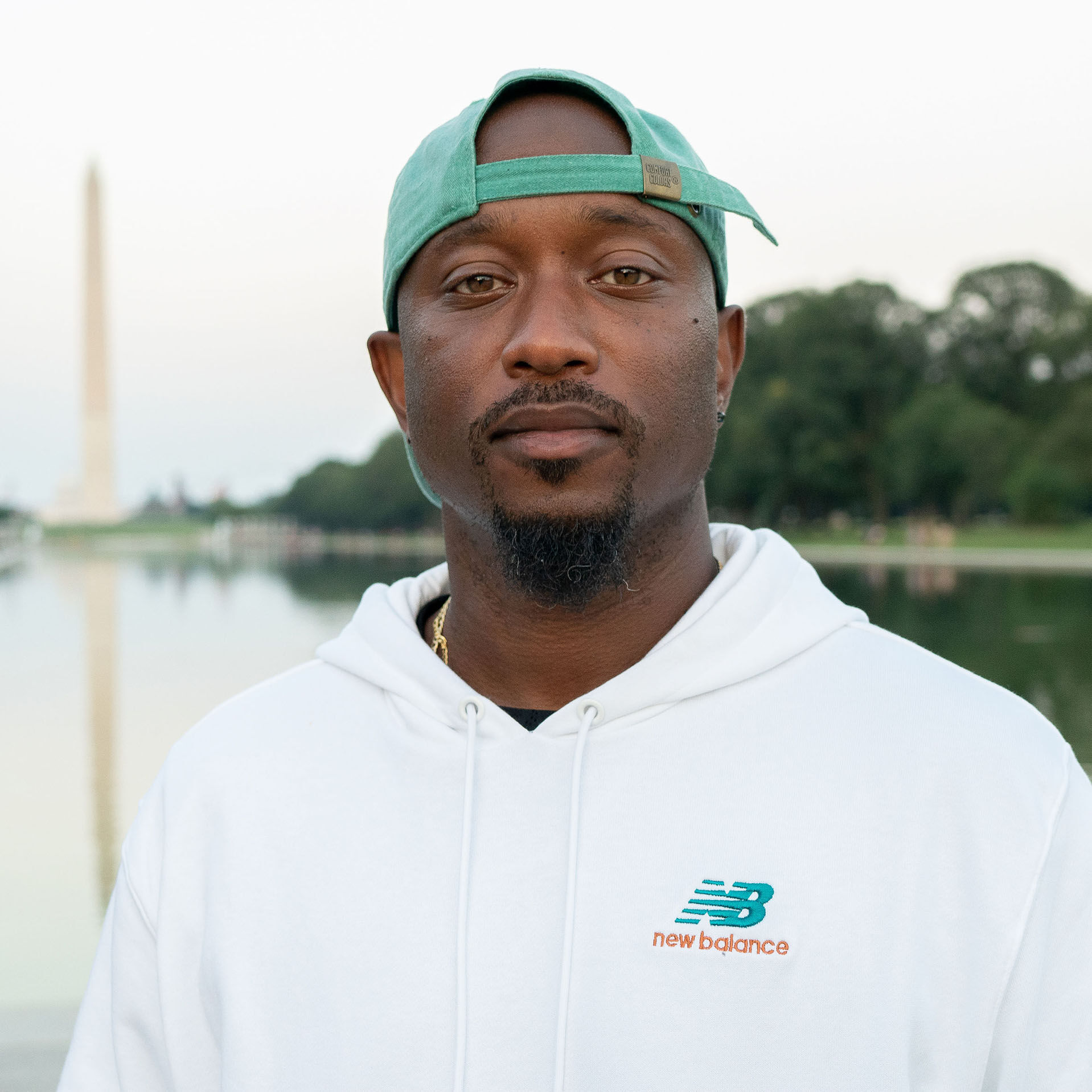 Runner and Music Executive, Jeriel Johnson, wearing a white NB hoodie and a green backwards hat, with the Washington Monument in the background